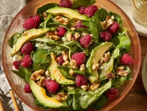 Raspberry spinach salad with avocado and walnuts served fresh in bowl